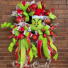 the grinch christmas wreath is hanging on a brick wall