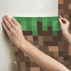 two hands are holding a piece of paper that looks like a minecraft creeper