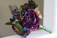 a bridal bouquet with purple flowers and peacock feathers on a white mantle in a living room