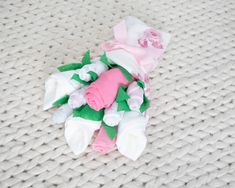 a pile of pink and white flowers sitting on top of a knitted cloth covered surface