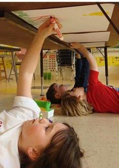 two people laying on the ground with their arms in the air and one person reaching for something