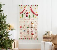 a christmas calendar hanging on the wall next to a tree and presents in front of it