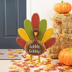 a wooden turkey sign sitting on top of a table next to hay and pumpkins