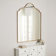 a white dresser with a mirror on top of it and a vase in front of it