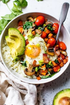 a bowl filled with rice and vegetables next to an avocado on the side