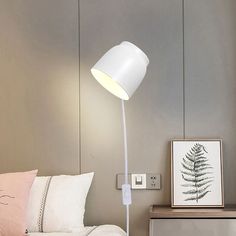 a white floor lamp sitting on top of a bed next to a night stand and nightstand