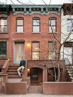 a man sitting on the steps in front of a brick building with stairs leading up to it