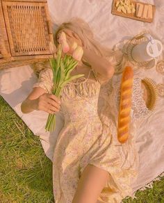 a woman laying on top of a blanket holding flowers