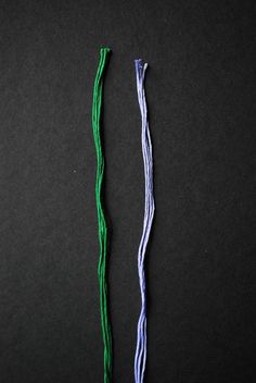 two different colored threads on a black surface, one is green and the other is blue