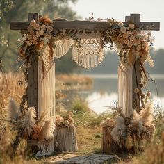 an outdoor wedding set up with flowers and feathers on the grass next to a body of water