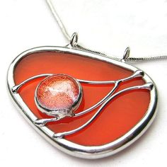 a pendant with a red and white glass piece on it's back end, hanging from a silver chain