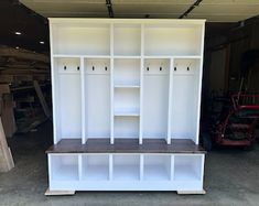 a white bookcase with shelves and benches in a garage area next to other items