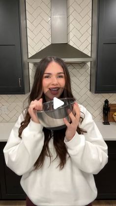 a woman holding a metal bowl in front of her face and making a funny face