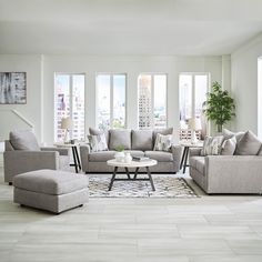 a living room filled with lots of furniture in front of windows and a rug on the floor