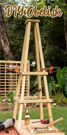 a wooden easel sitting on top of a table in the grass with tools next to it