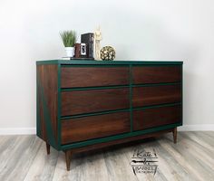 a wooden dresser sitting on top of a hard wood floor next to a white wall