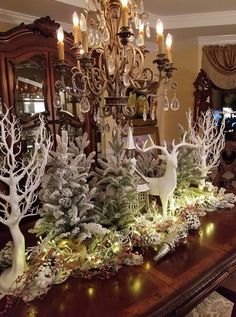 a dining room table decorated for christmas with deer figurines and greenery on it