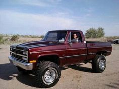 a woman sitting in the drivers seat of a red pick up truck