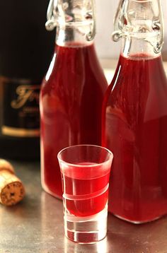 two bottles and a glass filled with red liquid