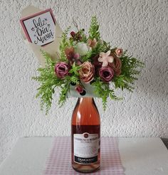 a bottle of wine sitting on top of a table next to a vase filled with flowers