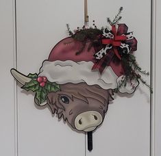 a cow with a christmas hat on it's head hanging from a door handle