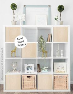 a white bookcase filled with lots of books next to a wall mounted mirror and potted plants