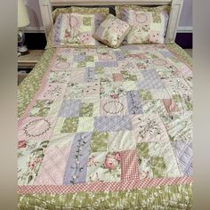 a bed with pink, green and blue quilted bedspread