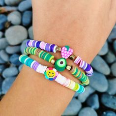 a woman's arm with several bracelets on it and rocks in the background