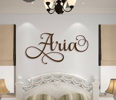 a white bed sitting under a chandelier next to a wall mounted light fixture