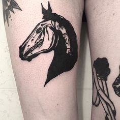 a woman's legs with tattoos on them and a horse head in the background