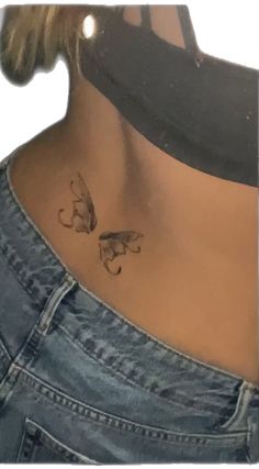 the back of a woman's neck with two small butterflies on her left side