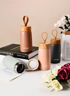 three different types of vases sitting on top of a table next to flowers and books