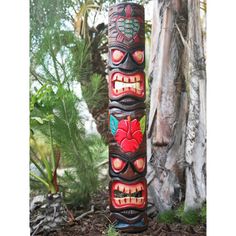 a totem pole with two faces painted on it's sides and flowers in the middle