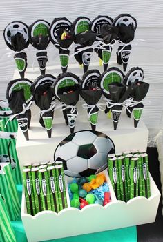 a table topped with lots of cups and soccer balls on top of each cupcake