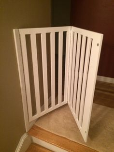 an open white gate on the stairs in a room with wood floors and carpeting