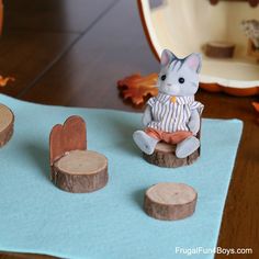 a cat figurine sitting on top of a piece of wood next to some cut out hearts