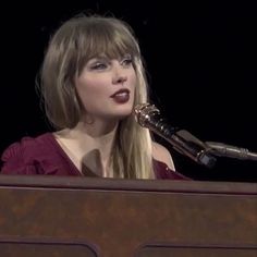 a woman in a red dress is speaking into a microphone