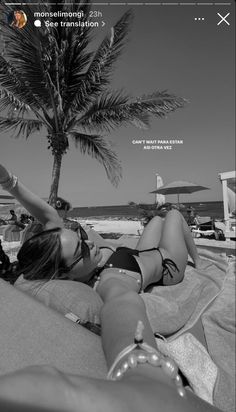 a woman laying on top of a beach next to a palm tree