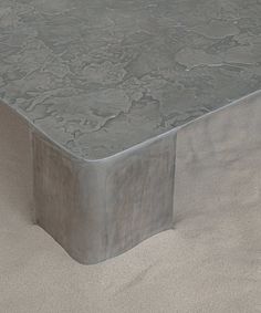 a table that is made out of concrete and has a square shape on it's surface