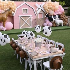 a table set up for a party with balloons and farm animals on the wall behind it