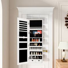 an open door to a white cabinet with lots of bottles and glasses on the shelves