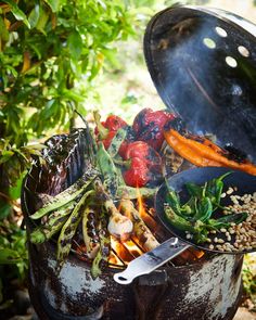 an outdoor grill with various vegetables cooking on it