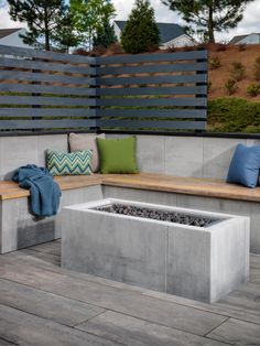 a fire pit sitting on top of a wooden floor next to a bench and pillows