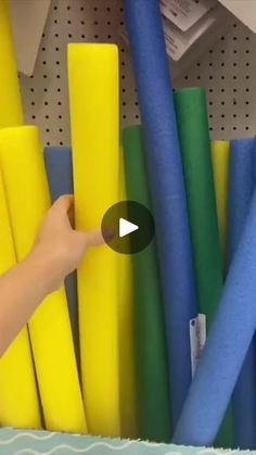 a person is pointing at some colored plastic tubes in a storage area with other items on the shelves