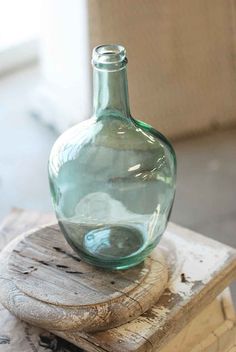 a green glass bottle sitting on top of a wooden block