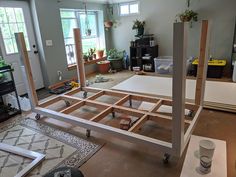 an unfinished bed frame in the middle of a room with plants and other items on the floor