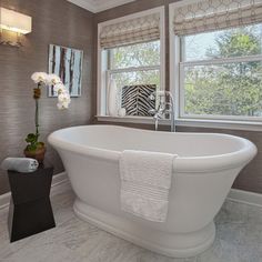 a white bath tub sitting in a bathroom next to two windows with zebra prints on them