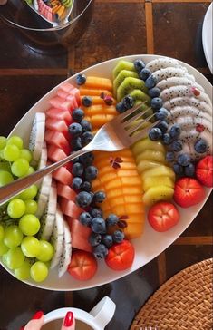 a plate full of different types of fruit on a table with a knife and fork