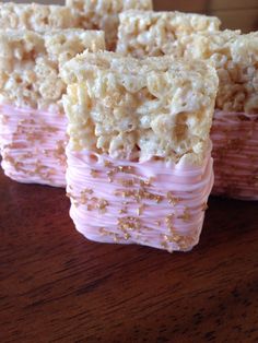 rice krispy treats stacked on top of each other with pink icing and gold sprinkles