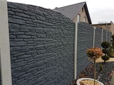 a stone wall next to a sidewalk with potted plants